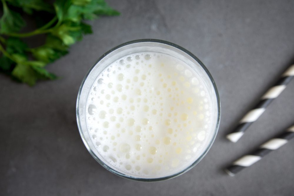 Fresh plain homemade yougurt (yogurt, youghurt, kefir, ayran, lassi) in glass with herbs over gray background, copy space. Probiotic cold fermented dairy drink.